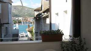 A balcony with a view of a coastal town, a potted plant, and a chair. - Klaudija’s Charming Apartments & Rooms - Room 4 (Trogir)