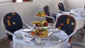 A dining area with a table set for two, featuring a fruit platter, plates, cutlery, and glasses. - Klaudija’s Charming Apartments & Rooms - Room 4 (Trogir)