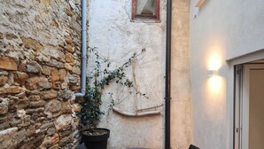 A stone wall, a potted plant, a hanging chair, and a table with chairs in an outdoor setting.