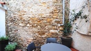 A stone wall with a round table and chairs in a courtyard.