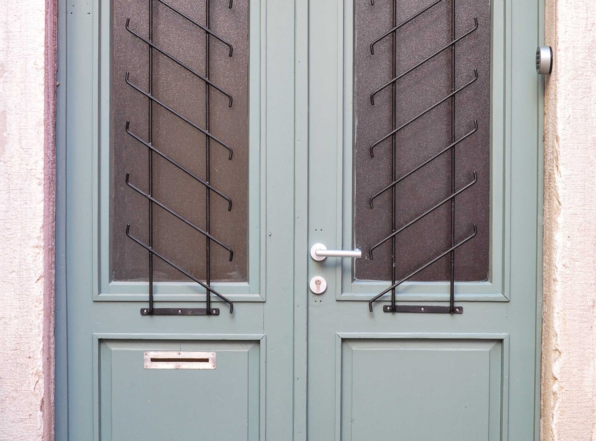 Puertas dobles con un sistema de estanterías metálicas en los paneles de vidrio.