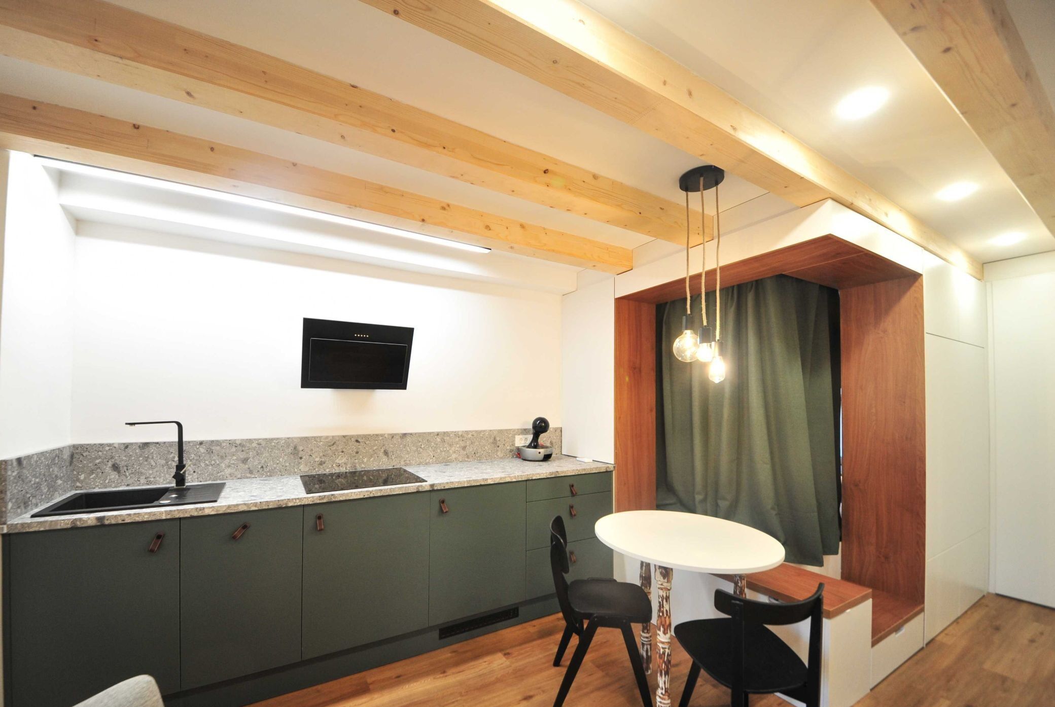 A modern kitchen with a built-in stove, a sink, and a dining area with a table and chairs.