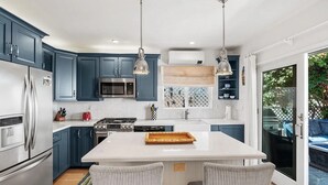 A modern kitchen with blue cabinets, stainless steel appliances, and a central island.