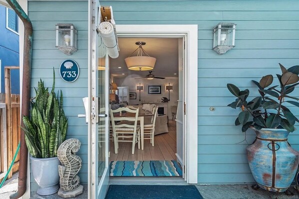 Una casa de estilo costero con un letrero con el número 733, un comedor con candelabro y una planta grande en maceta.