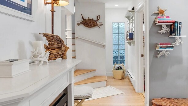 A modern interior with a staircase, a wall-mounted crab decoration, a lamp, and a bookshelf with books and decorative items.