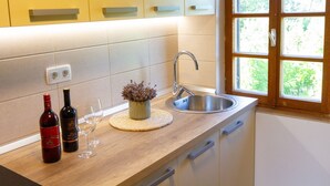 A kitchen with a wooden countertop, a stainless steel sink, and a window with a view of greenery.
