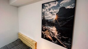 Ett sovrum med en säng, en tavla med ett berglandskap som hänger på väggen och ett sluttande tak.