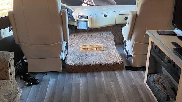 Een interieur van een camper met een keukenhoek, zitplaatsen en een slaapgedeelte.