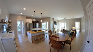 A spacious kitchen with wooden stools, a dining table, and pendant lighting.