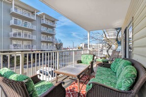 Un balcon doté de meubles en osier, d’une table et offrant une vue sur un immeuble à plusieurs étages.