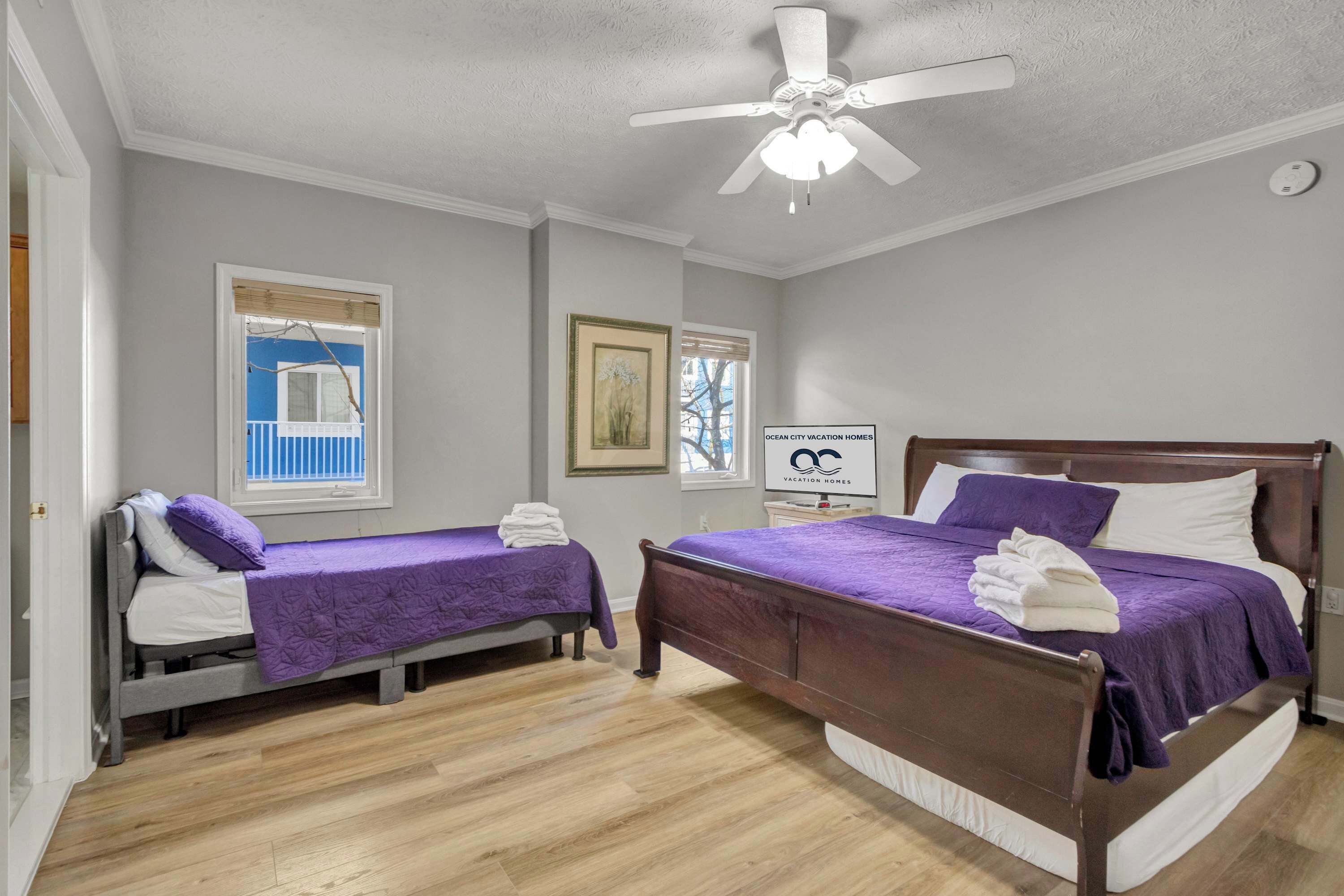 A bedroom with two single beds, a ceiling fan, and a window with blinds.