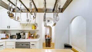 Una cocina con armarios blancos, una encimera de madera y varios electrodomésticos.
