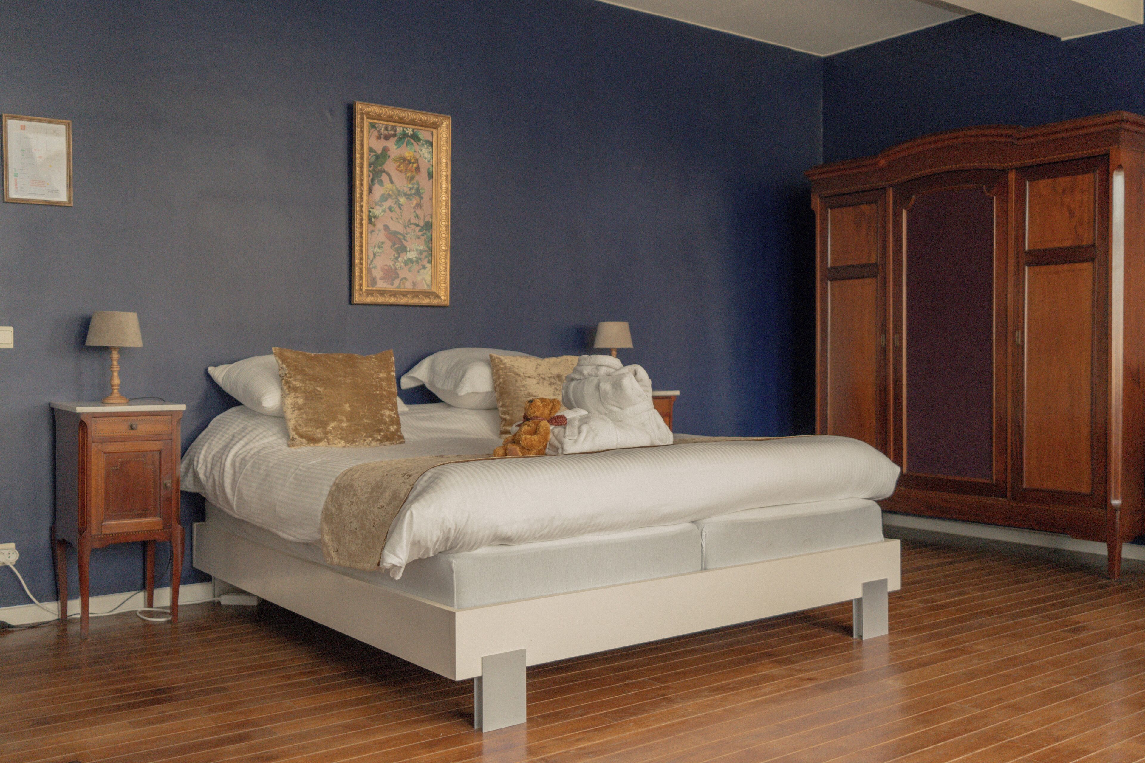 Een slaapkamer met een bed, een houten garderobe en een nachtkastje.