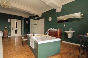 Un baño amplio con una bañera grande, un lavamanos y un espejo.