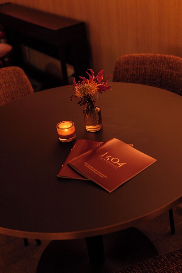 A round table with a candle, a vase with flowers, and a menu. - Hotel Restaurant Steenhuyse (Oudenaarde)