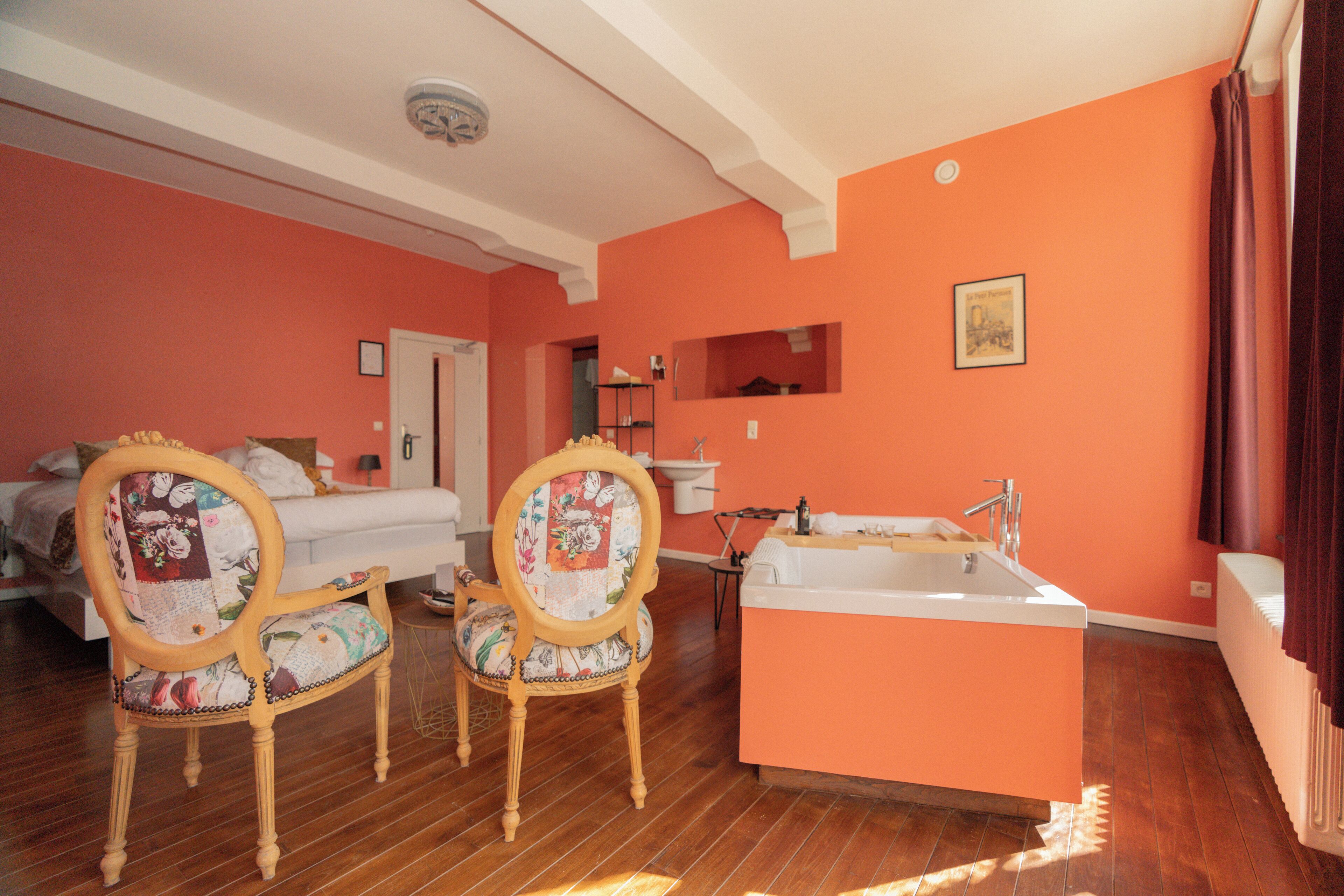 Ein Zimmer mit einem Bett, zwei Stühlen, einem kleinen Tisch, einem Waschbecken und einer Badewanne.