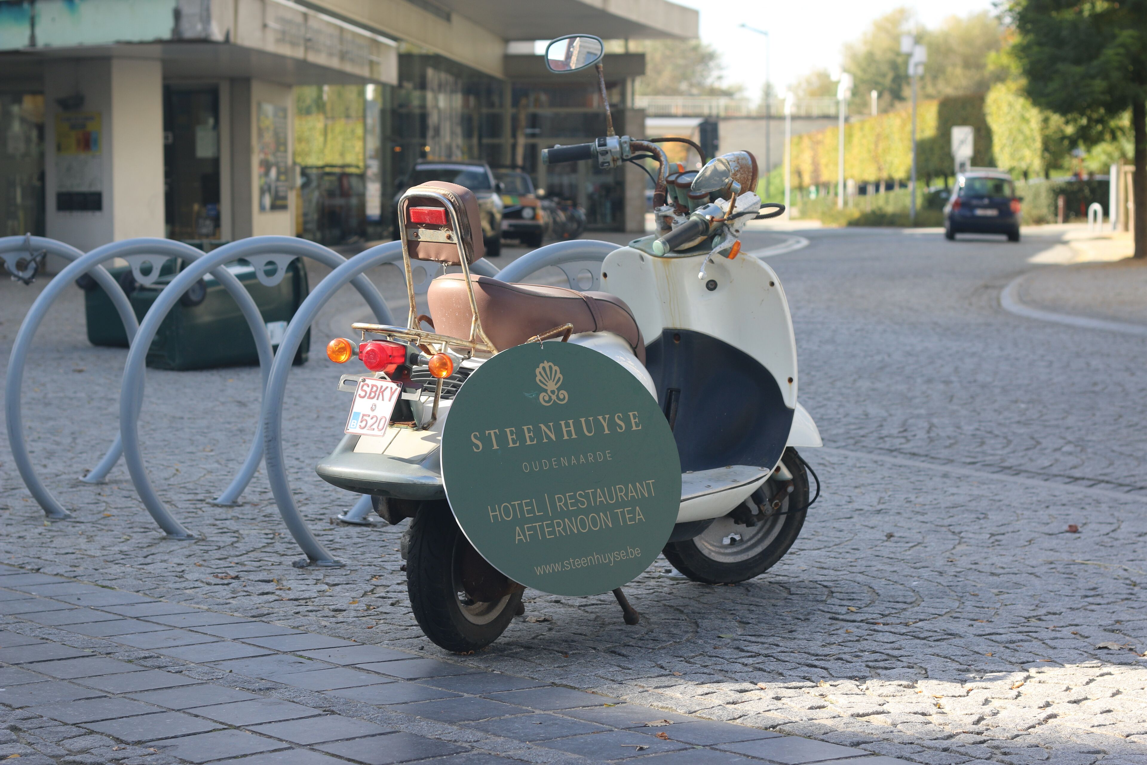 A scooter with a sign advertising a hotel and restaurant.