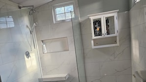 Un baño moderno con ducha de vidrio, inodoro y una pequeña ventana.