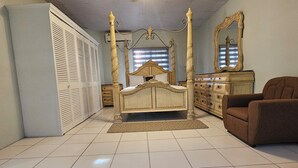 Un dormitorio con una cama con dosel, un tocador, una silla y un ventilador de techo.
