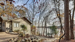 A cabin with a stone pathway leading to a wooden deck overlooking a lake. - Lakefront Hot Springs Village Home w/ Private Dock (Hot Springs)