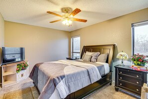 A bedroom with a bed, a TV, a nightstand, a dresser, a ceiling fan, and a window. - Large Yard, Fire Pit & Games: Grandview Haven! (Grandview)