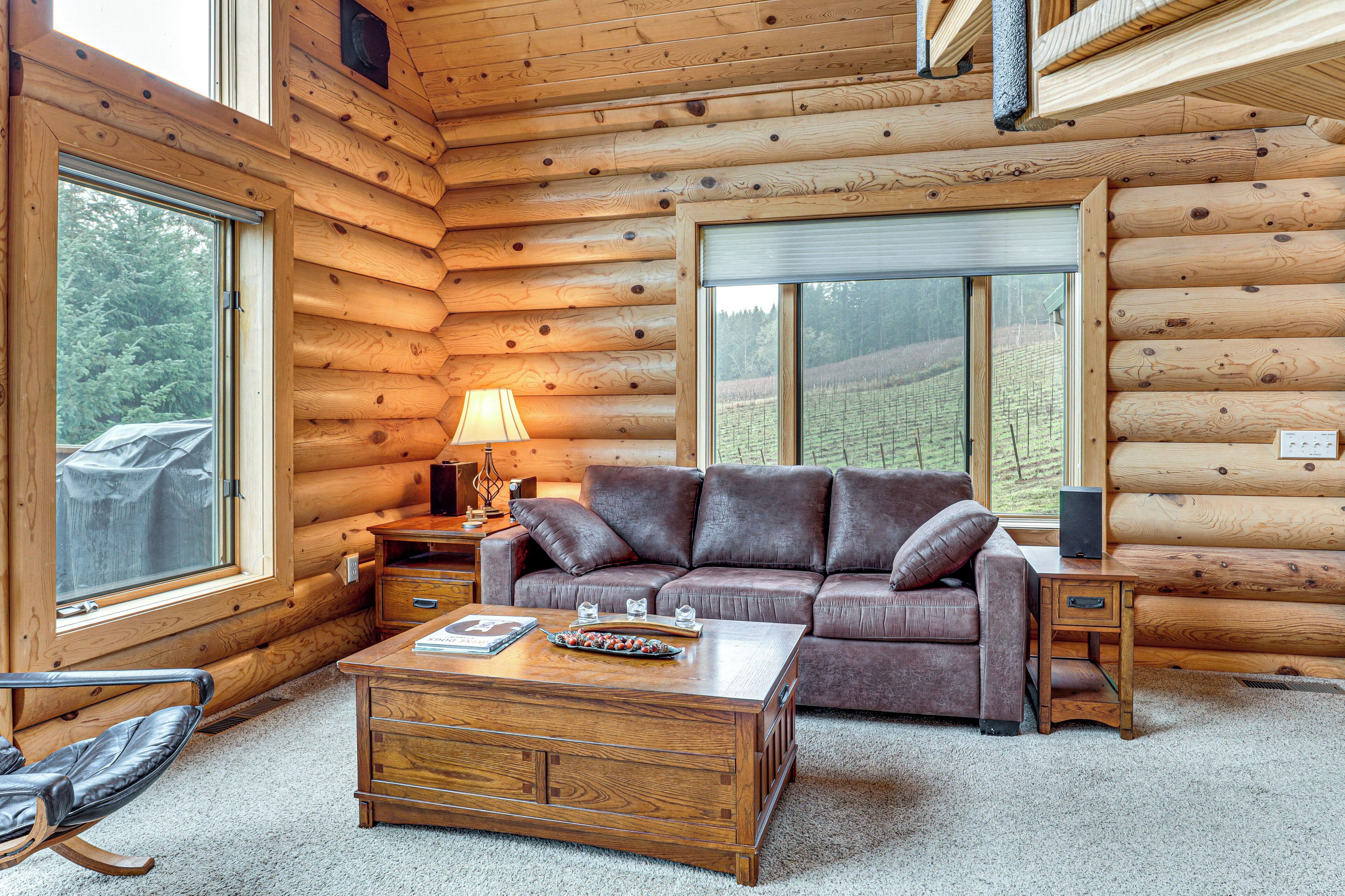 A log cabin interior with a leather sofa, wooden coffee table, and a lamp.