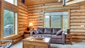 A log cabin interior with a leather sofa, wooden coffee table, and a lamp.