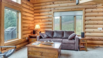 A log cabin interior with a leather sofa, wooden coffee table, and a lamp.