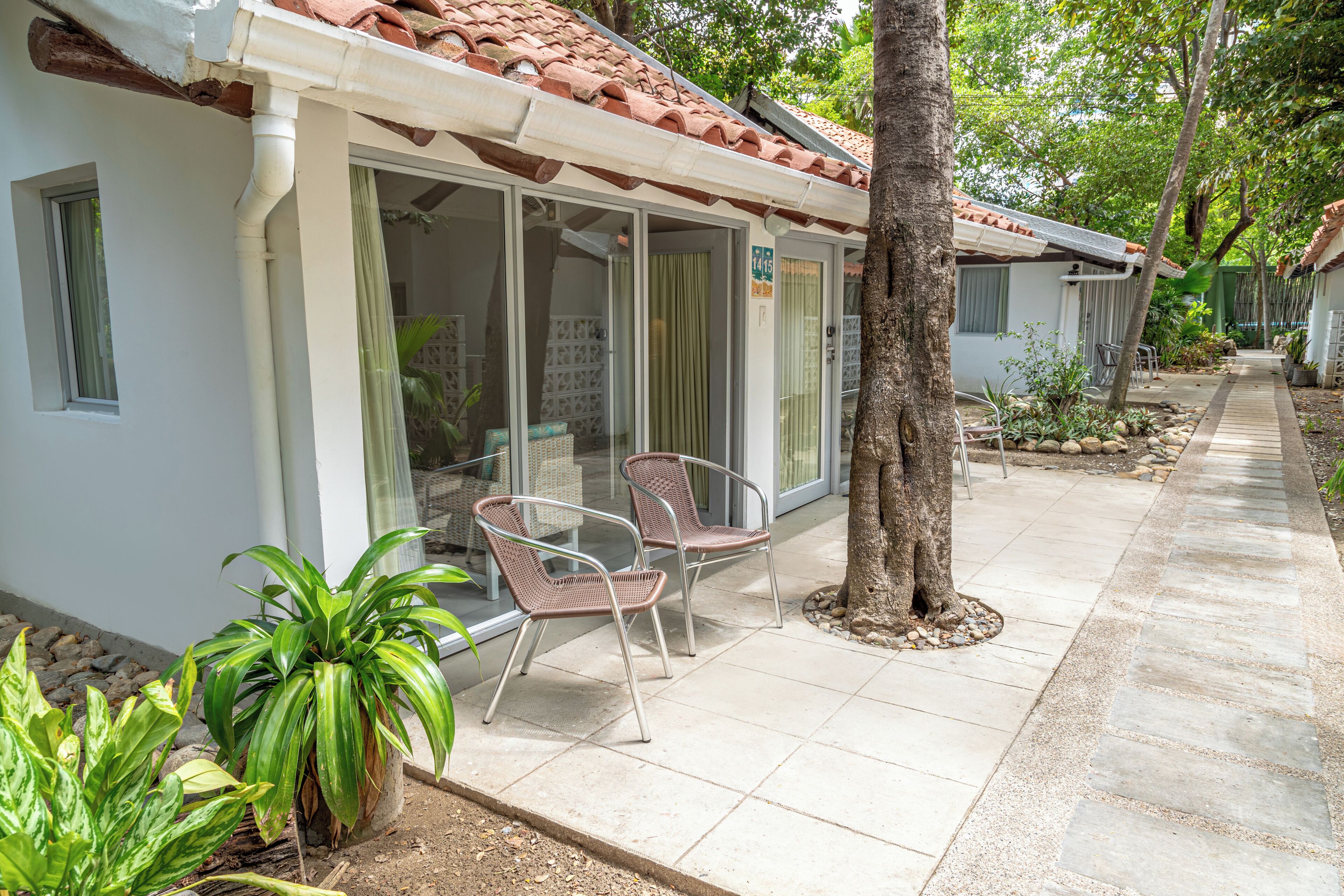 A covered outdoor seating area with chairs and a glass door entrance.