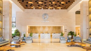 A modern lobby with a reception desk, seating area, and a wooden ceiling design.