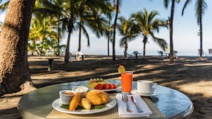 A table with food and drinks on a beach with palm trees in the background.