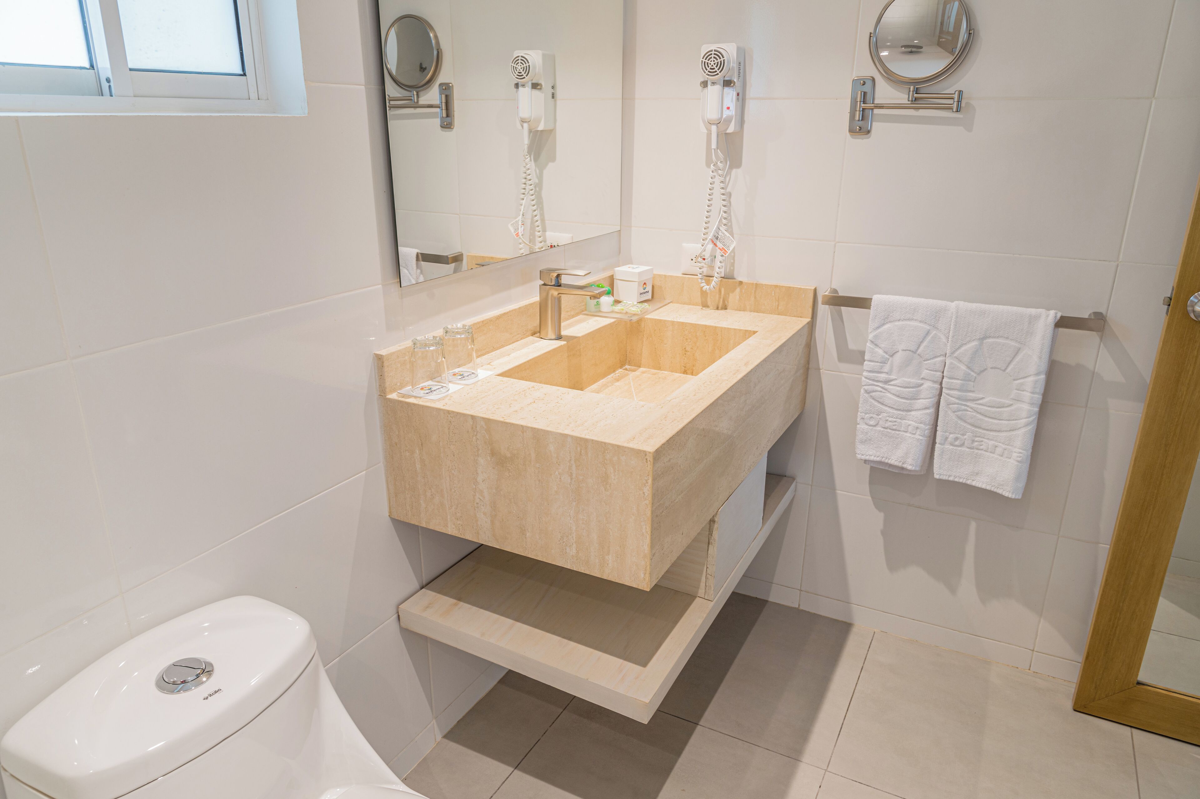 A modern bathroom with a beige sink, a toilet, and a towel rack with two towels.