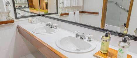 Un baño de hotel con dos lavamanos, un espejo grande y un tocador de madera.
