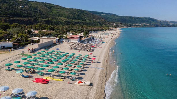 A beach with rows of umbrellas and beach chairs, a sandy shore, and a clear blue sea. - Villaggio Residence Emmesse Trilocal 3 Rooms (Zambrone)