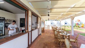 A restaurant with a counter, bar area, and outdoor seating with wicker chairs and tables. - Villaggio Residence Emmesse Trilocal 3 Rooms (Zambrone)