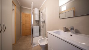 Une salle de bain équipée d’une douche, de toilettes, d’un bidet et d’un lavabo.