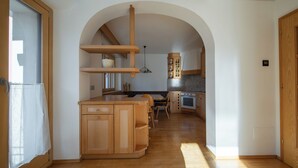 Une cuisine avec des meubles en bois, une table à manger et un luminaire suspendu.
