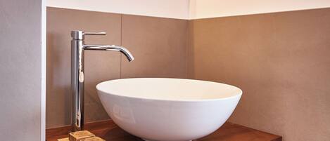 A modern bathroom with a large oval mirror, a white vessel sink, and a wooden vanity.