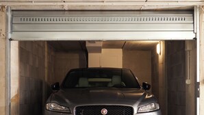 A car parked inside a garage with a metal door and a visible license plate. - Orti29 Luxury Stay. A cozy home within walking distance of the center of Bologna (Bologna)
