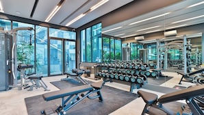 A modern gym with various exercise equipment, large windows, and a view of greenery outside. - B307 - 1 Bedroom Condo Pool View Near Ao Nang Beach (Krabi)