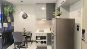 A compact kitchen with a refrigerator, a sink, and a dining area with chairs. - B307 - 1 Bedroom Condo Pool View Near Ao Nang Beach (Krabi)