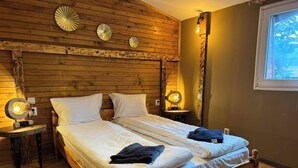 A wooden bed with two pillows and a blanket, two bedside tables with lamps, and a window with a view. - Chalet Iskar Borovets (Samokov)