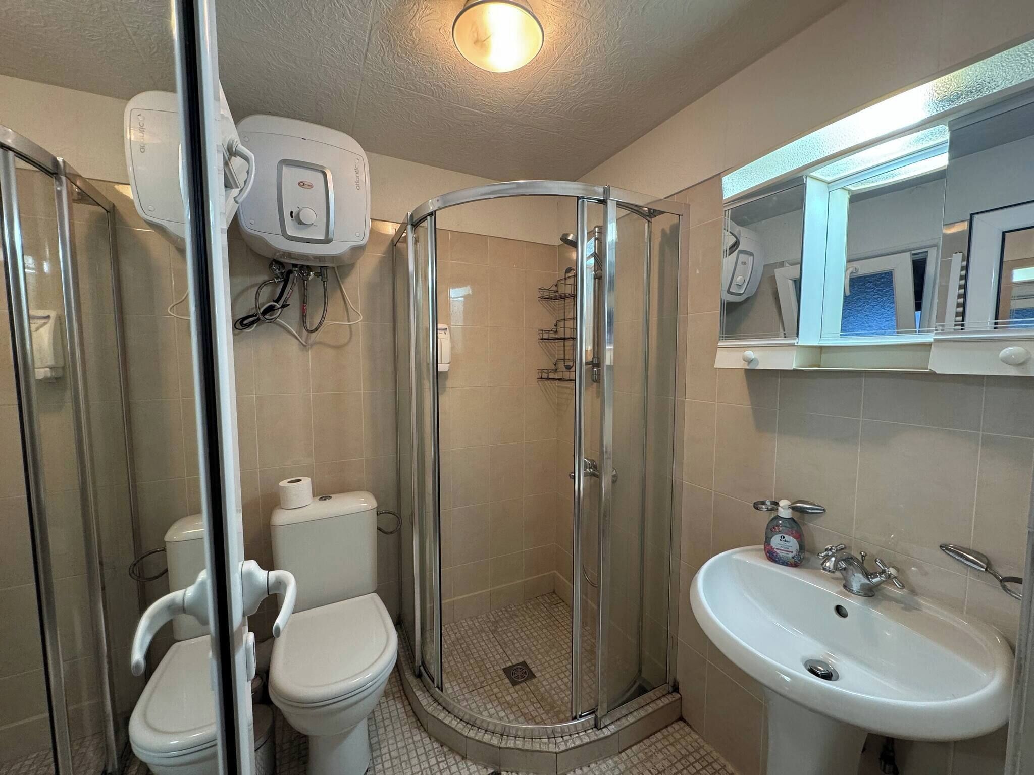 A bathroom with a glass-enclosed shower, a toilet, and a sink.