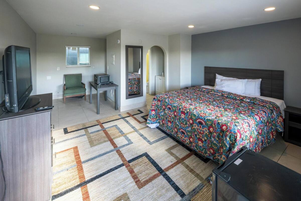 Una habitación de hotel moderna con una cama grande, televisión, escritorio y una silla.