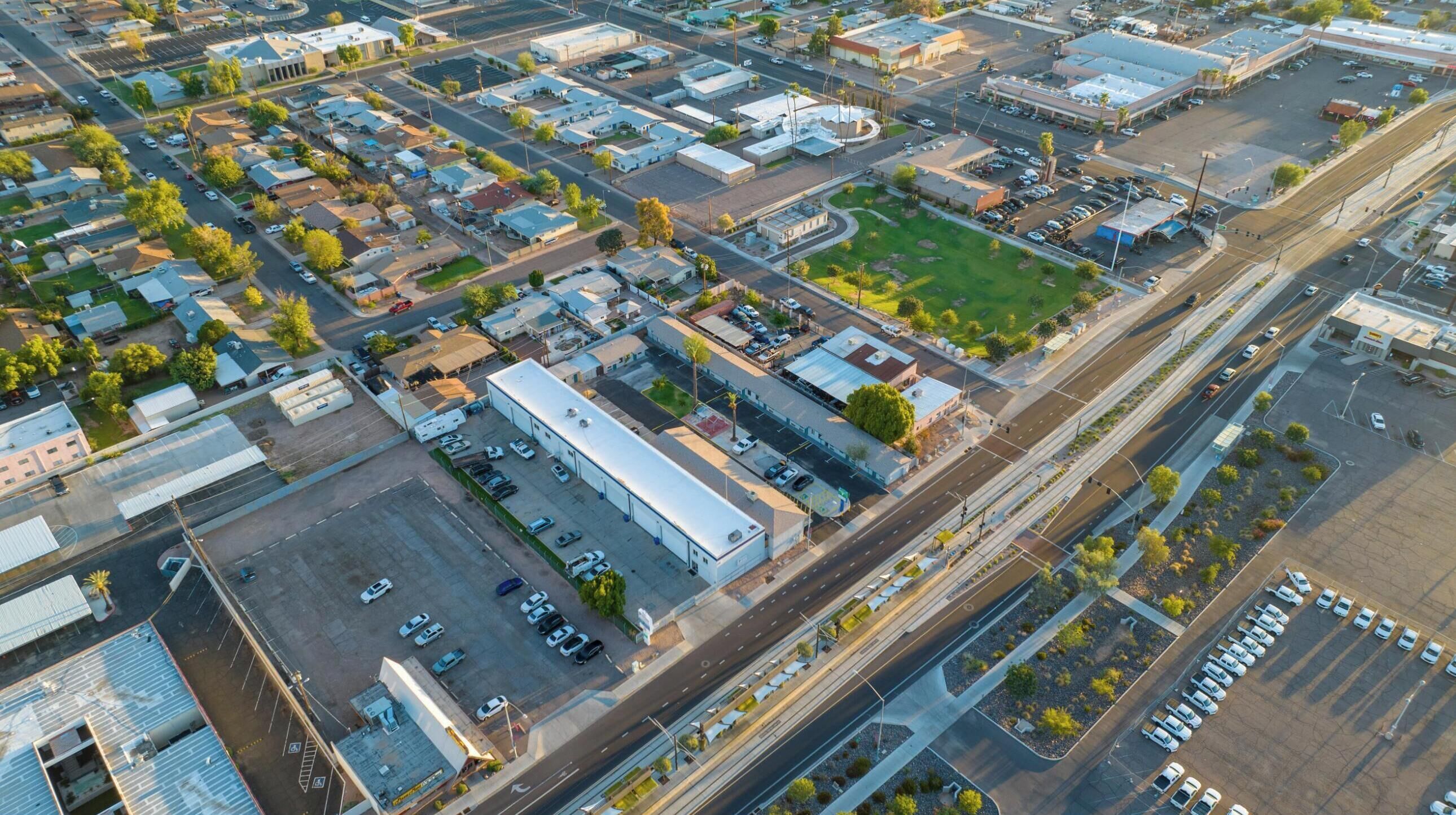 Vista aérea de una zona comercial con varios edificios, estacionamientos y carreteras.