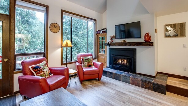 A cozy living room with a fireplace, large windows, and a television. - Snowater Condo - You'll be Sitting in the Lap of Luxury (Deming)