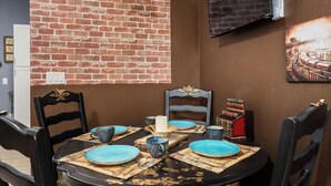 A dining area with a brick wall, a hanging light fixture, and a framed picture on the wall.
