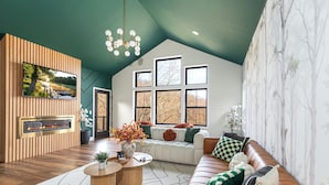Una sala de estar moderna con chimenea, ventanas amplias y techo alto.