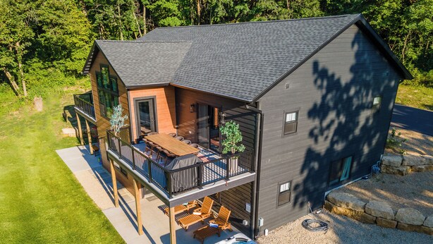 Una casa de dos pisos con balcón, jacuzzi y terraza con mobiliario exterior.