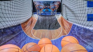 Un terrain de basket avec deux paniers, un plancher en bois et plusieurs ballons de basket.